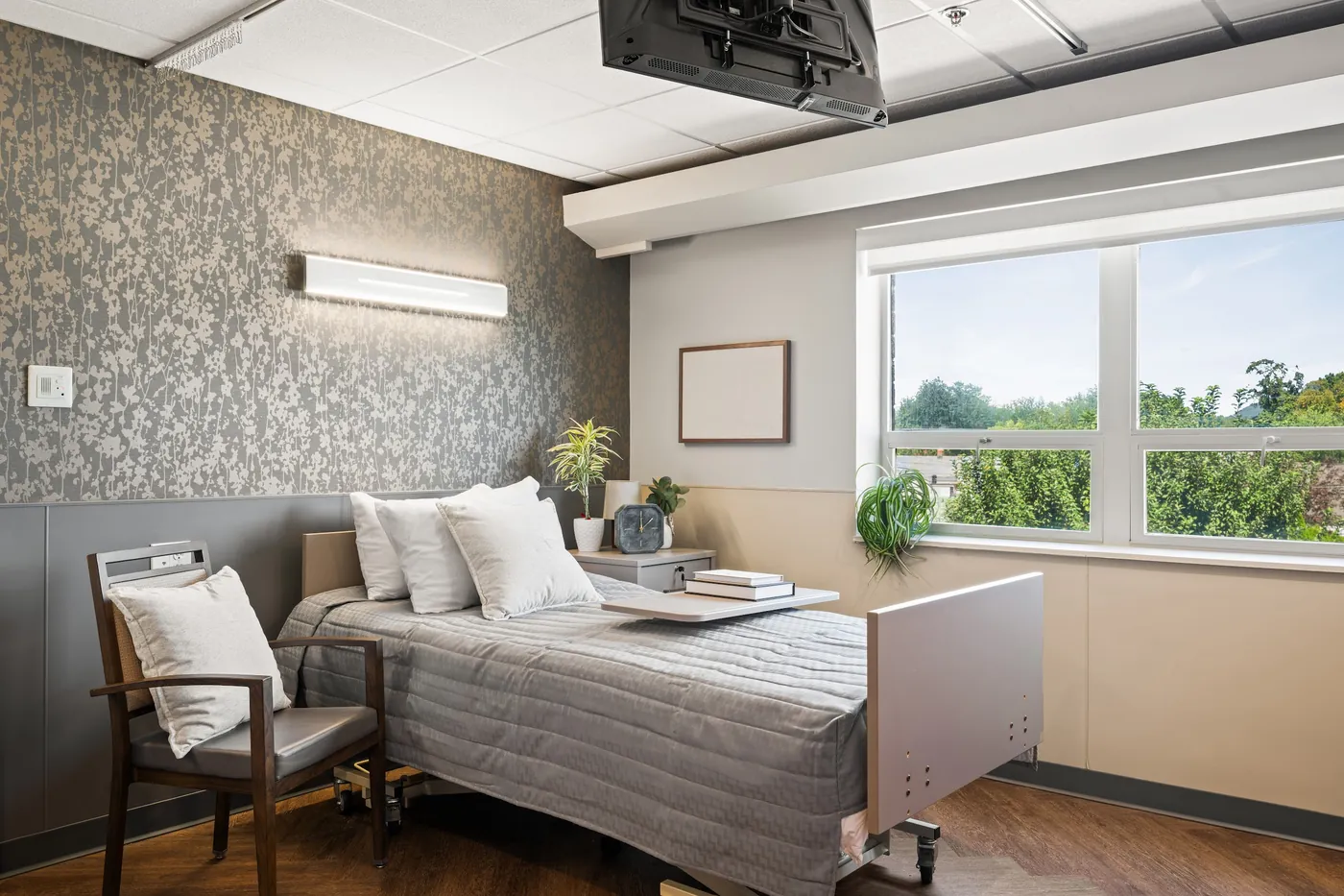 Newly renovated resident room with a made bed and armchair by the window