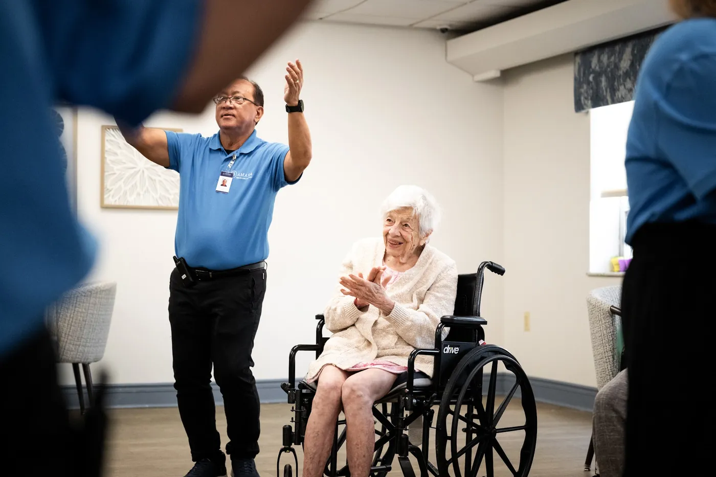 Team member cheering alongside a smiling resident during an activity