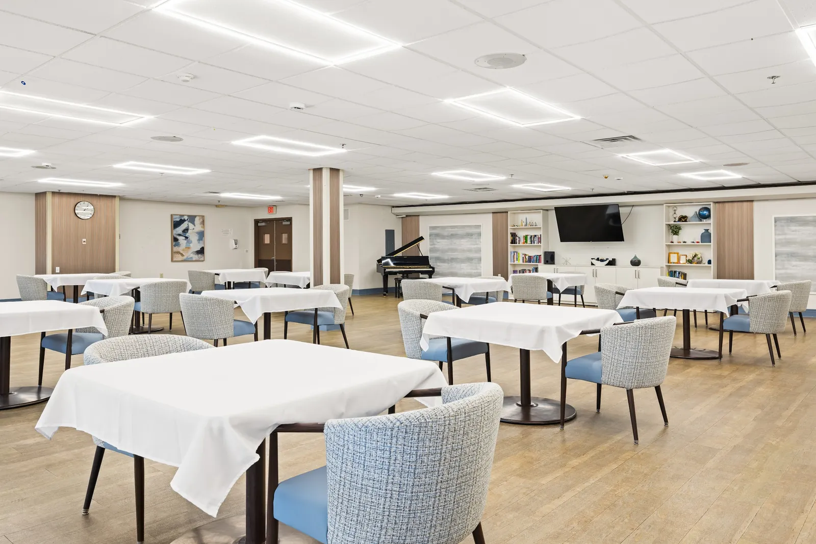 Dining room with white-clothed tables and a piano