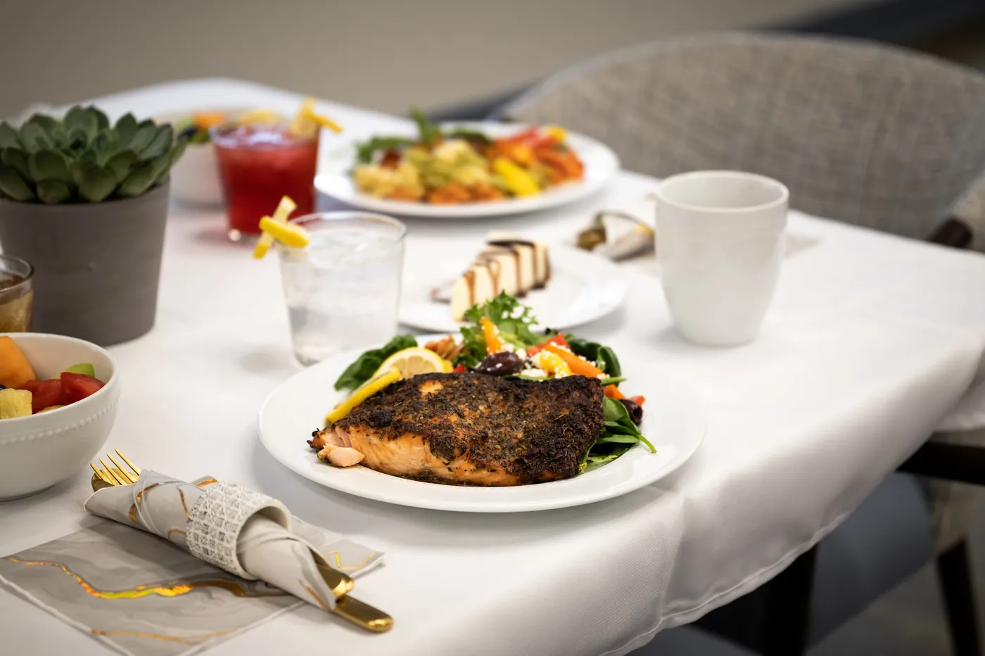 Freshly plated seared salmon and sides on a white-clothed dining table