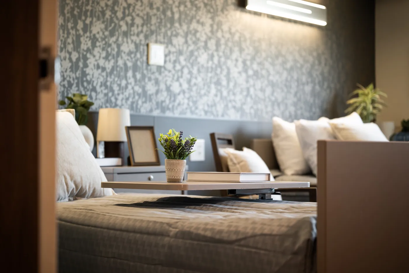 Newly renovated resident room with a comfortable bed and warm bedside lighting