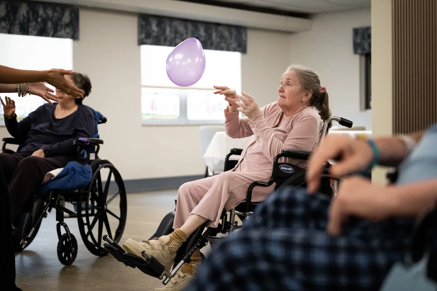 Resident reaching up to catch a balloon during a therapy activity